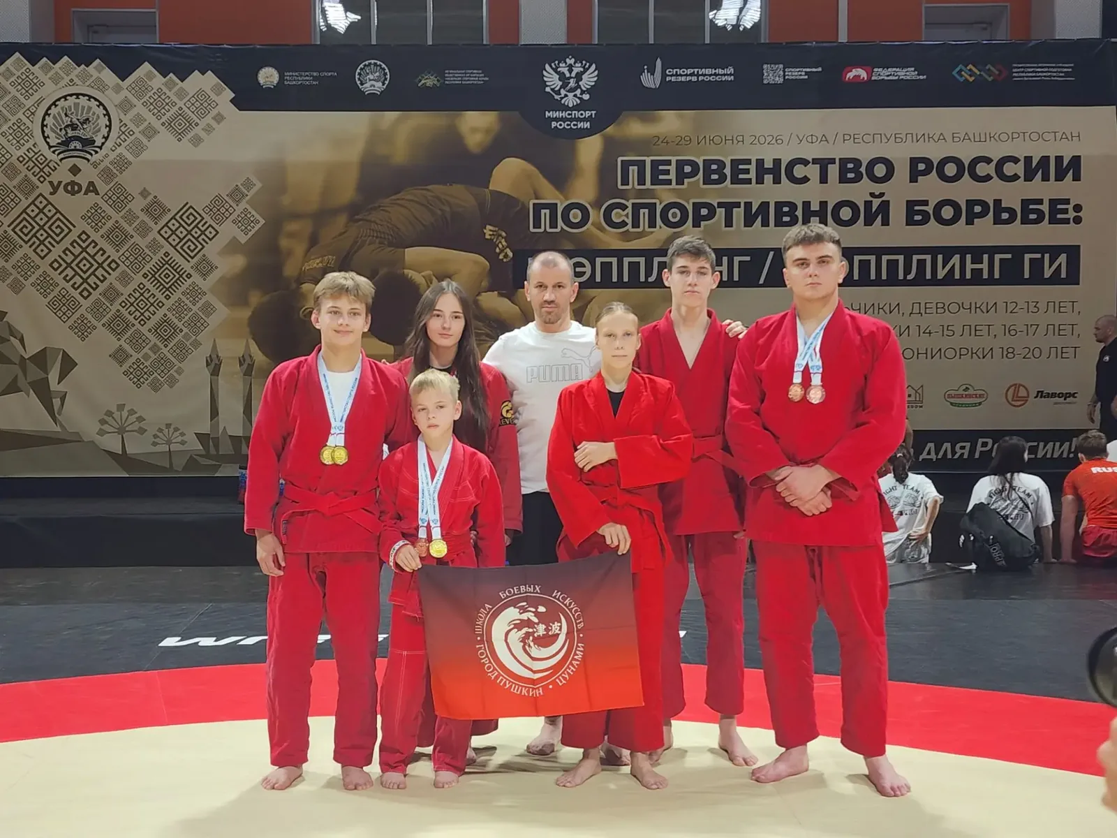 Команда с медалями и флагом «Цунами»